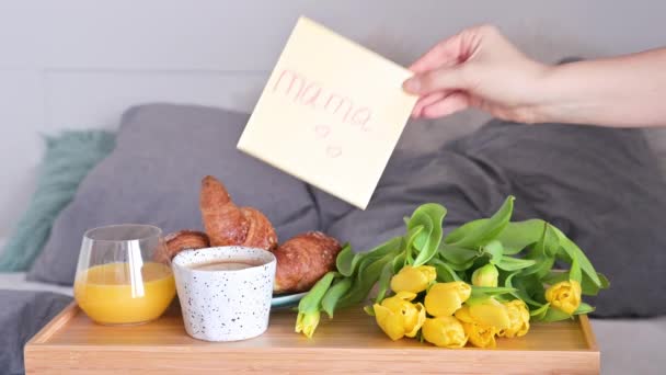 Prezent dla mamy. Mama dostała niespodziankę w Dzień Kobiet. Śniadanie do łóżka i bukiet żółtych kwiatów dla mamy. Tekst angielski - Mama. — Wideo stockowe