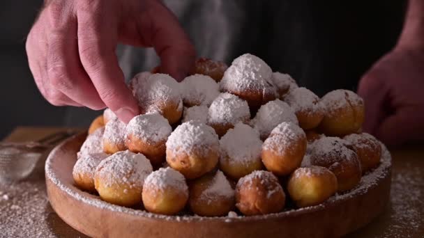 Um homem parte um doce pão. Castagnole assado com açúcar em pó. Doces tradicionais na mão. Comida de rua, biscoitos redondos com açúcar para o carnaval de Veneza. período de carnaval em itália — Vídeo de Stock