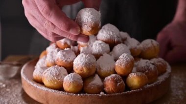 Bir adam tatlı bir çörek kırar. Fırında kastagnole ve pudra şekeri. Geleneksel tatlı hamur işleri. Sokak yemekleri, Venedik karnavalı için şekerli yuvarlak bisküviler. İtalya 'da karnaval dönemi 