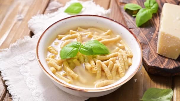 Passatelli i buljong - pasta tillagad i kyckling buljong. En pasta bestående av brödsmulor, ägg, riven parmesanost. Typiskt för Pesaro, Urbino och Emilia Romagna. Horisontell skjutning. — Stockvideo