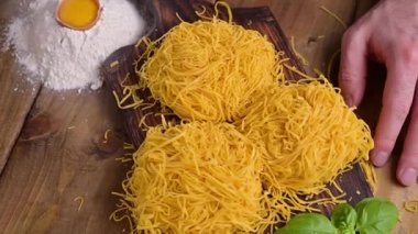 Tagliatelle makarnası incedir. Melek Saçlı geleneksel İtalyanca. İtalyan yumurtalı makarna, ev yapımı ve ahşap bir masada taze. İtalya 'nın kuzeyinin kırsal mutfağı. Sosyal ağlar için dikey video.