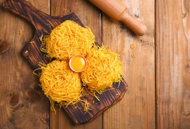 Tagliatelle makarnası incedir. Melek Saçlı geleneksel İtalyanca. İtalyan yumurtalı makarna, ev yapımı ve ahşap bir masada taze. İtalya 'nın kuzeyinin kırsal mutfağı. Dikey fotoğraf.