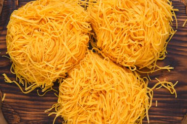 Tagliatelle makarnası incedir. Melek Saçlı geleneksel İtalyanca. İtalyan yumurtalı makarna, ev yapımı ve ahşap bir masada taze. İtalya 'nın kuzeyinin kırsal mutfağı. Yukarıda..