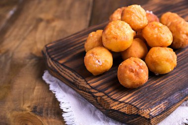 Ahşap arka planda pudra şekerli fırında castagnole. Sokak yemekleri, Venedik karnavalı için şekerli yuvarlak bisküviler. İtalya 'daki karnaval döneminde geleneksel tatlı hamur işleri. 