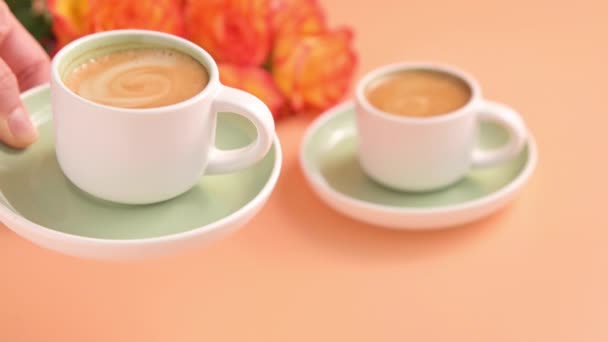 Verse aromatische espresso koffie met schuim. Koffie pauze voor twee en een boeket bloemen. Geurende zwarte koffie. Het meisje zet de beker op tafel. slow motion — Stockvideo