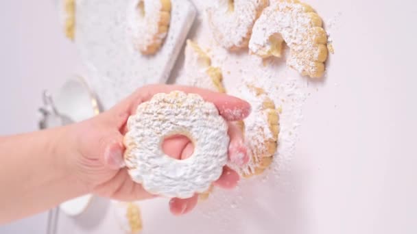 Canestrelli, traditionelle ligurische Kekse in Kamillenform mit Puderzucker. Feiertagsgebäck aus Süditalien, Frostpasta in der Hand. Vertikales Video — Stockvideo