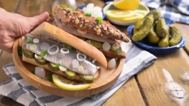 Hollanda ringası. Hollanda ringa balıklı tost, soğan, turşu. Geleneksel köy mezeleri ve deniz ürünleri. Hollanda 'da popüler yiyecekler. El bir sandviç alır..