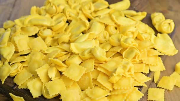 Malé ravioli se sýrem nebo masem na vaření ve vývaru, tradiční pokrm na oslavy v italském regionu Emilia Romagna. Čerstvé domácí těstoviny s náplní na dřevěném stole. — Stock video