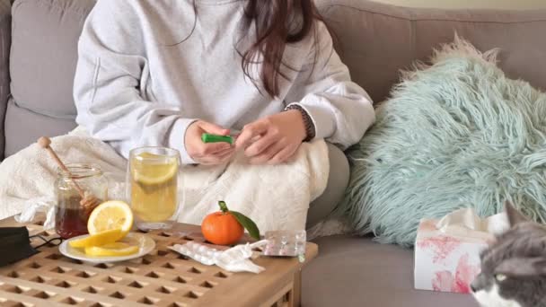 这个女孩病了，躺在床上，喝着柠檬茶。桌上有药丸和餐巾。在大流行期间治疗头孢病毒.健康概念. — 图库视频影像