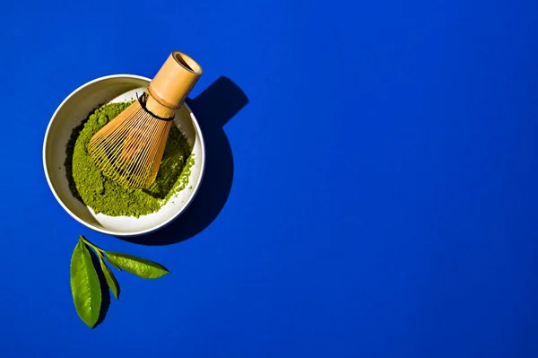 Matches tea and whisk on a blue background. Fresh tea leaves and everything for making a tea drink.
