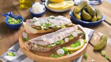 Hollanda ringası. Hollanda ringa balıklı tost, soğan, turşu. Geleneksel köy mezeleri ve deniz ürünleri. Hollanda 'da popüler yiyecekler. El bir sandviç alır..