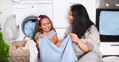 Anne ve küçük kızı keyifle yerde oturuyorlar., 