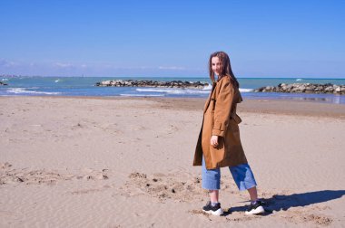 Bir plajın önünde duran bir adam. Güzel genç kız deniz kıyısında yürüyor. Duyguların dışavurumu. Turizm ve seyahat kavramı. Yüksek kalite fotoğraf