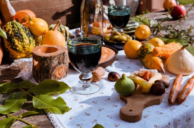 Sonbahar doğasında öğle yemeği için hazırlanmış bir masa, piknik. Hasat, sonbahar yemeği, şarap ve bardaklar. Açık hava toplantısı.