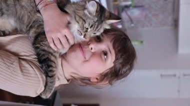 çocuk ve kedi. Bir çocuğun kollarında pofuduk kedinin yakın çekimi 