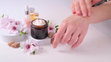 El kremi. Çerçevede kadın eli var, bir kız kremi badem ve tereyağıyla sürüyor. Hafif bir arkaplanda doğal kozmetik malzemeleri.