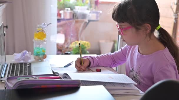 La bambina sta facendo i compiti. La studentessa studia a casa al computer. Apprendimento a distanza nella scuola primaria. — Video Stock