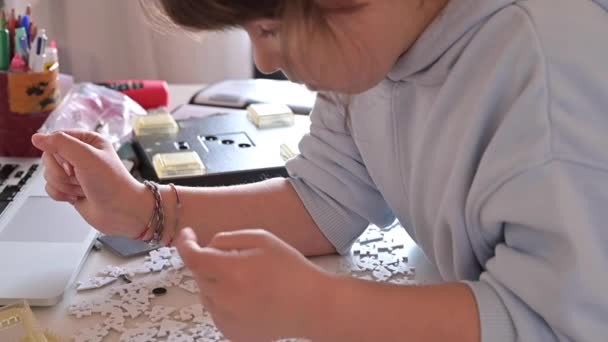 Sammle Rätsel. Kleine Mädchen spielen im Zimmer Brettspiele. Nahaufnahme einer Hand mit Details und Teilen aus einem 3D-Puzzle. — Stockvideo