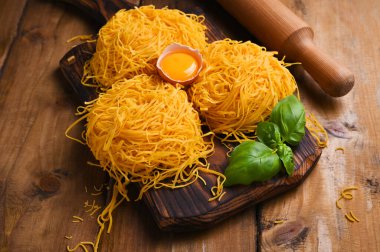 Tagliatelle makarnası incedir. Melek Saçlı geleneksel İtalyanca. İtalyan yumurtalı makarna, ev yapımı ve ahşap bir masada taze. İtalya 'nın kuzeyinin kırsal mutfağı. Dikey fotoğraf.