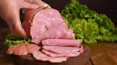 Mortadella. Ahşap bir masada fıstıklı büyük bir mortadella. Bir adam ince dilimler halinde sosis keser. İtalya 'nın Emilia Romagna bölgesinde ve Bologna şehrinde geleneksel et ürünleri.