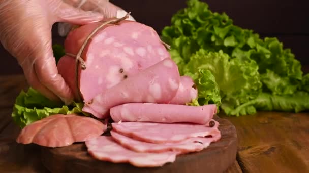 Mortadella. Grande mortadela com pistache em uma mesa de madeira. Um homem corta fatias finas de salsicha. Comida tradicional de carne na região da Emília Romanha na Itália e na cidade de Bolonha. — Vídeo de Stock