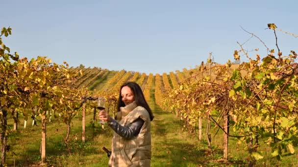 Magnífico viñedo en las colinas de Emmilia Romagna en otoño. Mujer con una botella de vino y una copa en una granja en Italia. Deslumbramiento del sol en el marco. Banner, formato largo. — Vídeos de Stock