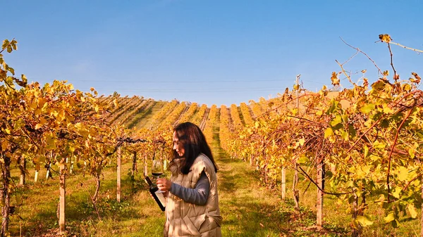 Mladá žena se sklenkou bílého vína na italských vinicích. Osoba nalévá víno. Volné místo pro text. — Stock fotografie