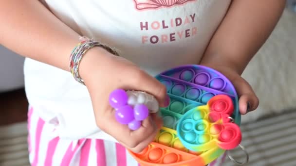 小女孩玩弹奏它的感官玩具。宝宝在五彩缤纷的彩虹上轻柔地轻拍硅胶泡. — 图库视频影像