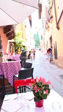 İtalya 'da bir sokak restoranı. İtalya 'daki Garda Gölü kıyısındaki eski şehir merkezinde kırmızı kareli masa örtüleri olan geleneksel kafe.. 