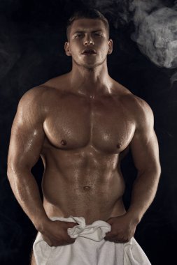 Seksi spor kaslı, kaslı adam beyaz havluyla siyah izole font arka planda dumanlı.