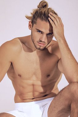 Seksi spor kaslı, kaslı, sarışın, uzun saçlı, beyaz iç çamaşırlı, beyaz tenli yazı tipi arka planlı.
