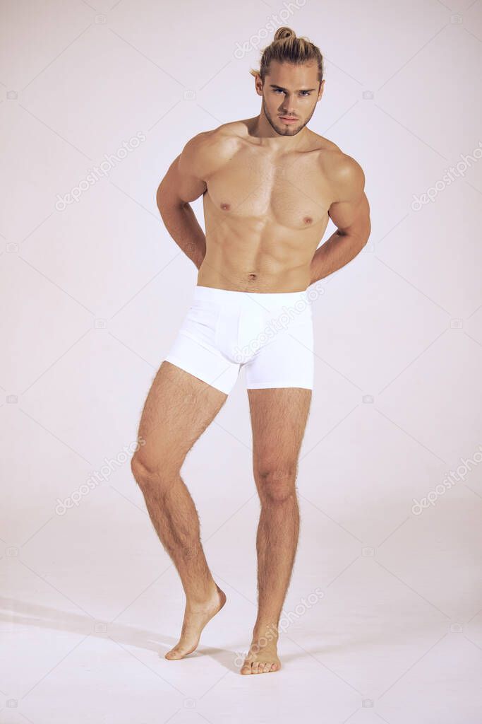Sexy sport muscle strongface blond guy with long hair in white underwear on white isolated  font background