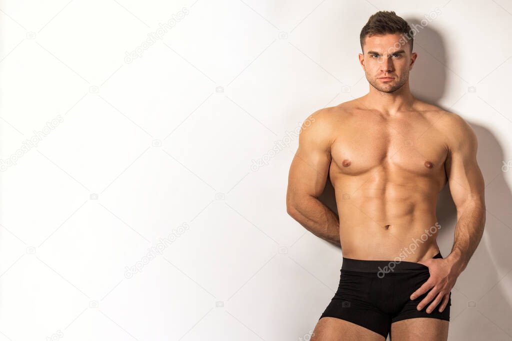 Strong stripped muscle male model in black boxers underwear on gray isolated font background