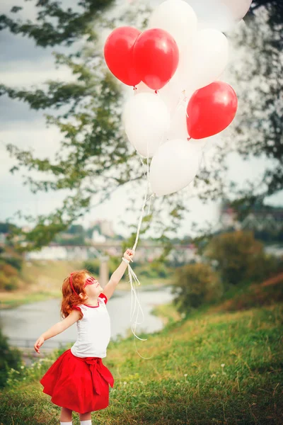 Little  beautiful curly girl with red and white ballons in the p — Stock Photo, Image