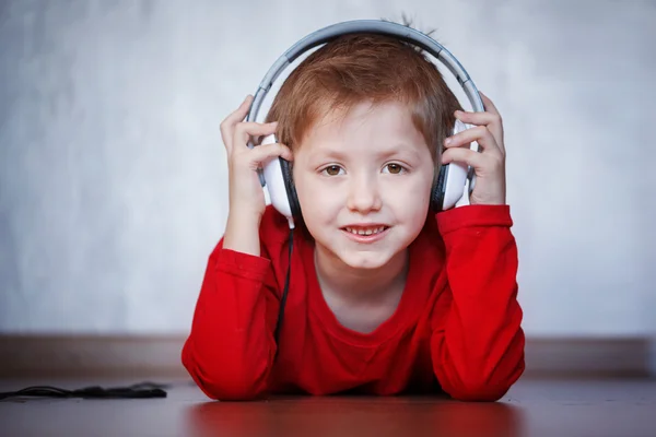 Lindo niño escuchando música en los auriculares y disfrutando —  Fotos de Stock