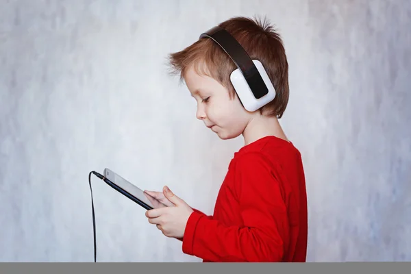 Bambino ragazzo ascoltare musica o guardare film con le cuffie a — Foto Stock