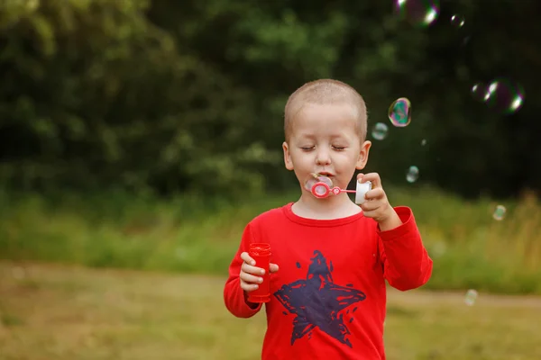 Ребенок надувает мыльные пузыри. Ребенок пускает пузыри на природу — стоковое фото
