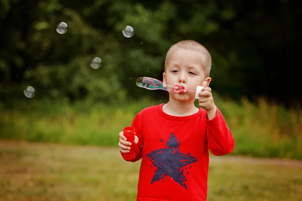 Child blowing a soap bubbles. Kid blowing bubbles on nature. — Stock Photo, Image