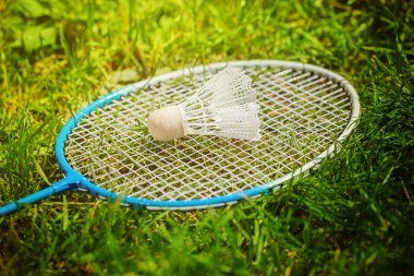 Yeşil çimenlerin üzerinde raketle ve badminton raket.