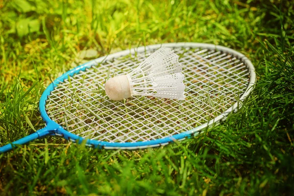 Kuželka a badminton raketa na zelené trávě. — Stock fotografie