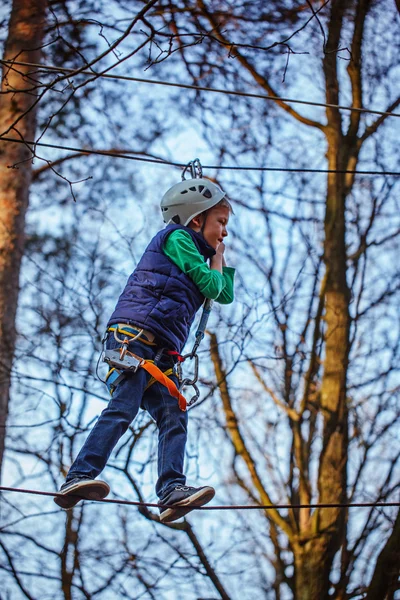 Fiatal, boldog gyermek fiú adventure parkban, biztonsági berendezések. — Stock Fotó