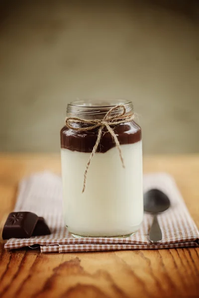 Mleczna jogurt z czekoladowa wieża i łyżka na serwetka i drewnianym tarasem — Zdjęcie stockowe