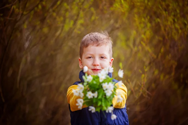 Портретный мальчик протягивает букет весенних цветов — стоковое фото