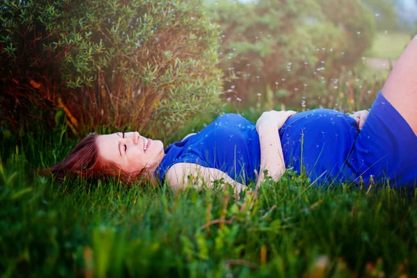 Zwanger meisje is in een gras leggen en dromen over haar pregna — Stockfoto