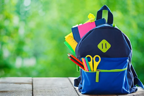 Zaino scuola completa su sfondo di legno e natura . — Foto Stock