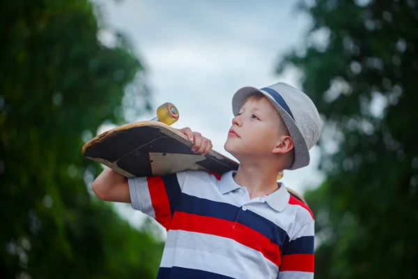 Lindo niño sosteniendo monopatín en la mano al aire libre . —  Fotos de Stock