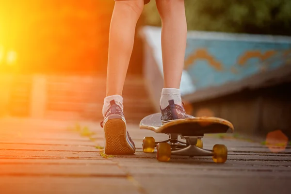 Pés de criança com skate na rua ao pôr do sol luz — Fotografia de Stock