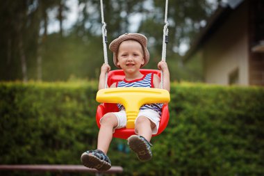 Eğleniyor ve açık playgroun üzerinde sallanan küçük boy gülümseyerek