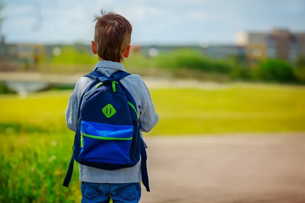 Ein kleiner Junge mit einem Rucksack geht zur Schule. zurück — Stockfoto