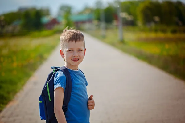 Pequeño colegial bonito sentado en la calle con su backpac — Foto de Stock